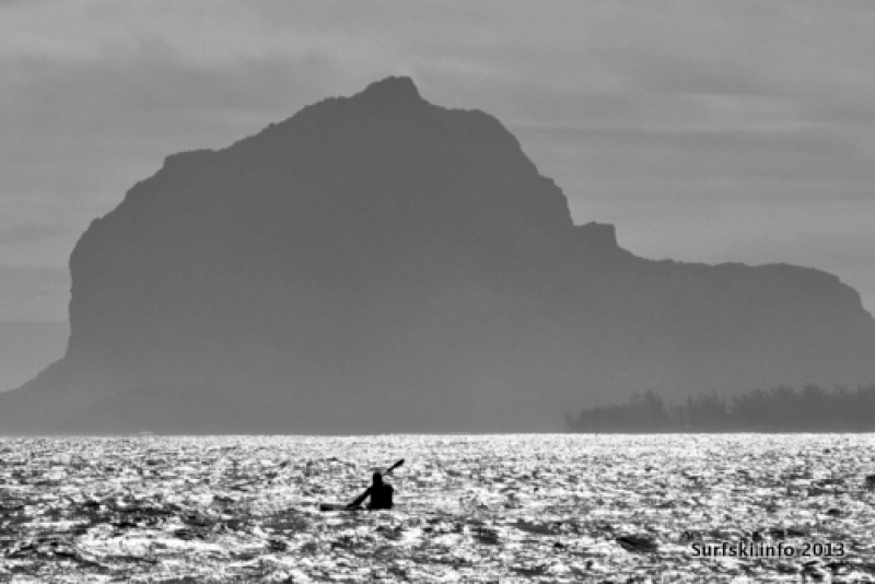 A paddler heads towards the distinctive shape of the Le Morne Brabant Mountain